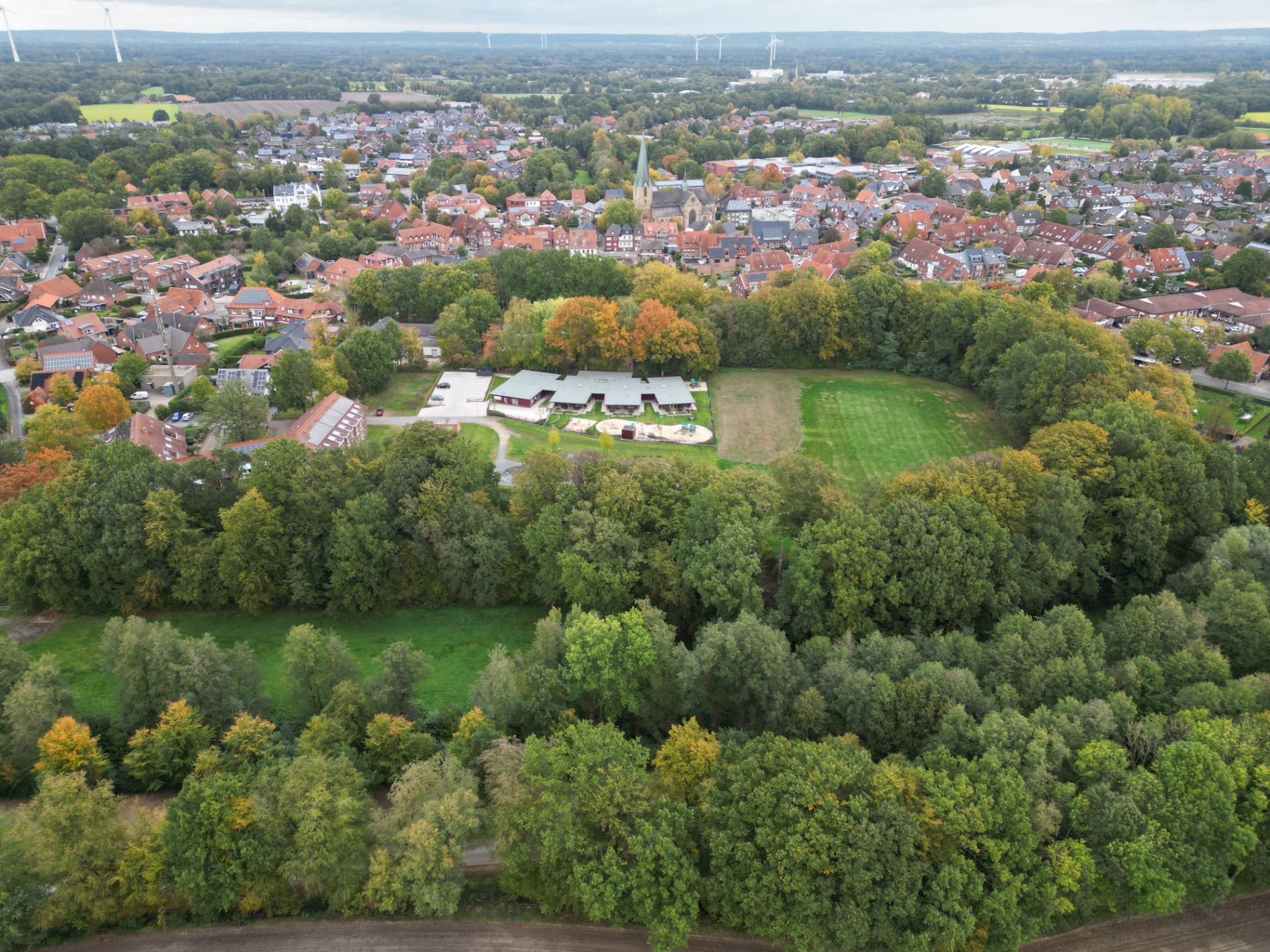 Luftbild des Saerbecker Ortskerns mit Kirche und Windrädern im Hintergrund